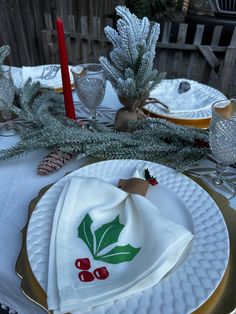 a christmas table setting with holly napkins and pine cones