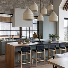 a large kitchen with lots of counter space and hanging lights above the bar area, along with wooden dining chairs