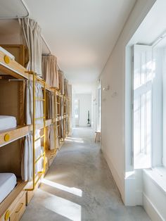 there are many bunk beds lined up in the room with curtains on each side and windows to the other side