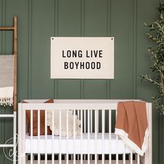 a baby crib with a sign that says long live boyhood on the wall