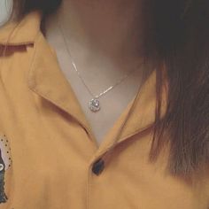 a close up of a person wearing a yellow shirt with a necklace on their neck