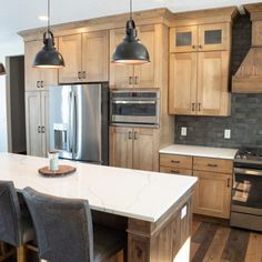 a kitchen with wooden cabinets and stainless steel appliances, including an island table surrounded by chairs