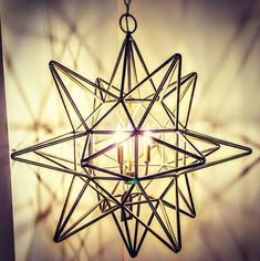 a star shaped chandelier hanging from the ceiling with two candles in front of it