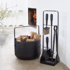 a fire place with logs in it next to a potted plant on the floor