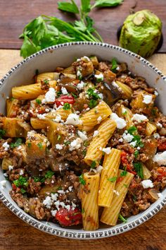 a bowl filled with pasta and meat on top of a wooden table