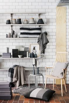 a living room with white brick walls and shelves filled with blankets, sweaters and pillows