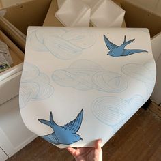 a person holding up a large sheet of paper with blue birds on it