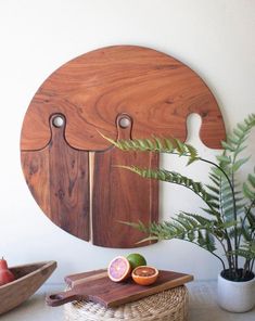 a cutting board with two knives and fruit on it next to a potted plant