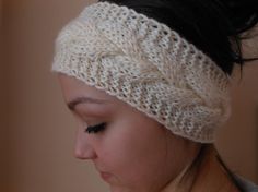 a close up of a woman wearing a knitted headband and looking down at her cell phone