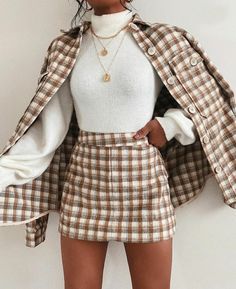 a woman wearing a white top and brown plaid skirt