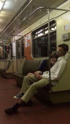 two people sitting on a subway train next to each other