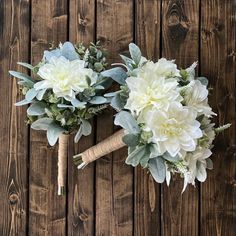 the bridal bouquet is made up of white flowers and greenery on a wooden background