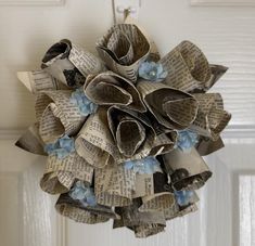 an origami wreath made out of old newspaper pages hanging from a door handle