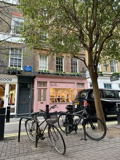 two bikes parked next to each other in front of a pink building on a city street