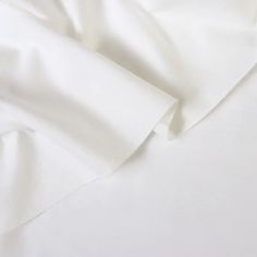 an unmade bed with white sheets and pillows