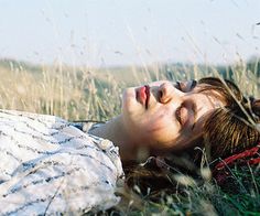 a woman laying in the grass with her eyes closed and head tilted to the side