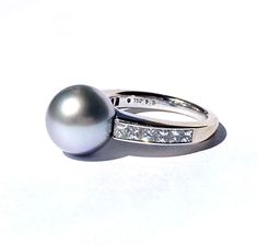 For your consideration, a stunning 18K white gold grey akoya pearl and diamond ring by Mikimoto from their Elements of Life series, the gray pearl and diamond combination representing Air.  The ring features a 10mm gray akoya pearl and .62 carats of princess cut diamonds at the shoulders the ring is in overall good vintage condition with some wear to the rhodium white gold finish and some mild surface abrasions to the pearl.  **Signature required for delivery.** Sized between 5.5 and 5.75, weigh Luxury White Akoya Pearl Diamond Ring, Luxury Akoya Pearl Drop Ring, Luxury Diamond White Akoya Pearl Ring, Mikimoto Pearl Ring, Luxury Pearl White Akoya Pearl Rings, Elements Of Life, Akoya Pearl Ring, Pearl Diamond Ring, Mikimoto Pearls