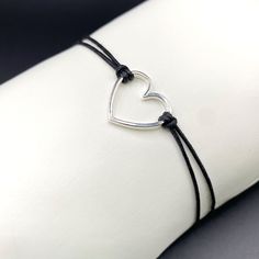 Wonderful friendship bracelet consisting of a large heart made of sterling silver, threaded with black cotton in macrame style. The unique piece of jewelry has a length of 16 cm and can be adjusted as desired. Show your deep connection with this beautiful friendship bracelet with a high-quality 925 sterling silver heart pendant. The adjustable black macrame bracelet ensures that it fits your wrist perfectly. An ideal gift for your love that is not only stylish but also carries a meaningful messa Adjustable Open Heart Everyday Bracelet, Adjustable Heart-shaped Sterling Silver Bracelet, Black Sterling Silver Bracelets With Adjustable Cord, Adjustable Sterling Silver Open Heart Bracelet, Sterling Silver Black Bracelet With Adjustable Cord, Black Sterling Silver Bracelet With Adjustable Cord, Silver Heart Friendship Bracelets, Silver Heart-shaped Friendship Bracelets, Black Thread Bracelet