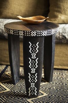 a wooden table sitting on top of a rug next to a couch with pillows in the background