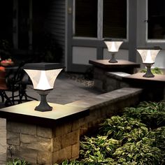 three outdoor lights sitting on top of a stone block in front of a patio area