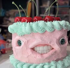 a pink cake with cherries on top and green icing, has two cherries on it's head