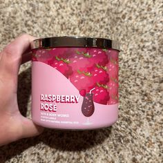 a hand holding a jar of raspberry rose yogurt on the ground