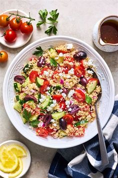 a salad with tomatoes, cucumbers, olives and feta cheese in a white bowl