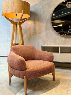 an orange chair sitting in front of a round mirror on the wall next to a lamp