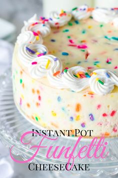 a cake with white frosting and colorful sprinkles on top is sitting on a glass platter