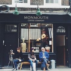 three people sitting on a bench in front of a coffee shop