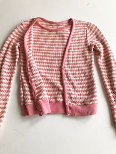 60’s pink/white striped waffle knit sweater has an extra sweater vest panel sewn on the interior, with cardigan construction on the exterior. The sweater has pink knit rib at the sleeve cuffs, hem, neckline, and button placket. The sweater has a button front exterior, but is slip on.ConditionOverall good, has a hole at the left underarm.MeasurementsBust 34”Waist 30”Shoulder 17”Sleeve length 23”Length 21” Pink Ribbed Fitted Cardigan, Fitted Ribbed Pink Cardigan, Pink Fitted Ribbed Cardigan, Vintage Sweater For Spring Layering, Pink Ribbed Cotton Sweater, Pink Ribbed Winter Cardigan, Pink Long Sleeve Retro Cardigan, Pink Crew Neck Cardigan For Layering, Pink Ribbed Sweater For Layering