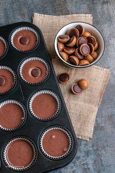 chocolate cupcakes in a muffin tin next to a bowl of almonds