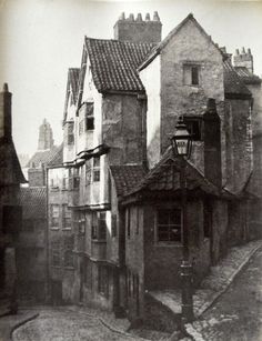 an old black and white photo of buildings on a street with cobblestone streets