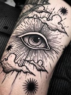 an all seeing eye tattoo on the arm with stars and clouds around it, in black ink