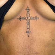 a cross tattoo on the back of a woman's stomach