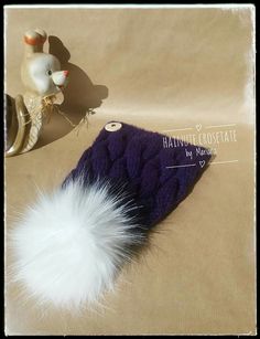 a purple hat with a white fur ball on it and a metal object next to it