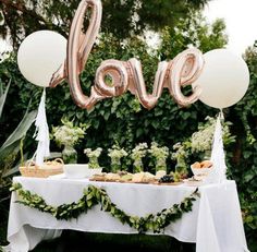 an image of a table with balloons that say love on it and some food in the foreground