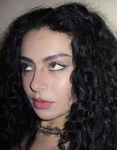 a close up of a person with long hair wearing a choker and eye makeup