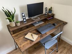 a computer desk with a keyboard, mouse and monitor on it next to a potted plant