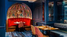 a restaurant with blue walls and red booths, wooden tables and colorful stained glass windows