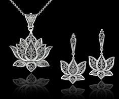 "This 925 sterling silver filigree art blossoming lotus flower pendant and dangle drop earrings set is a true work of art. The filigree silverwork is delicate and intricate, creating a beautiful open-air design that showcases the lotus flower in full bloom. The dangle drop style of the pendant and earrings adds a touch of movement to the overall design, making this set both stylish and eye-catching.       Whether you're dressing up for a special event or just want to add some beauty to your everyday look, this set is sure to make a statement. The sterling silver material also ensures that this set will last for years to come, making it a great investment piece for your jewelry collection. Earrings; The length of the earrings is 1.70\"  and the width is 0.90\". The total weight is 7.50 gr. Silver Dangle Fine Jewelry Sets, Traditional White Gold Jewelry Sets For Gift, Fine Jewelry With Filigree Dangle, Fine Jewelry Dangle Earrings With Filigree, Elegant Filigree Jewelry Sets, Sterling Silver Flower Shaped Jewelry Stamped 925, Sterling Silver Jewelry Sets With Intricate Design, Sterling Silver Jewelry Sets With Intricate Design For Gift, White Gold Pendant Jewelry Sets As Gift