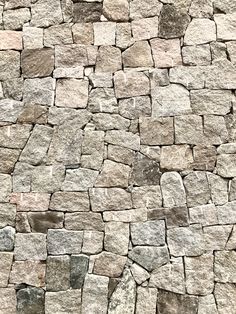 a stone wall that has been made out of small rocks and is grey with some brown spots