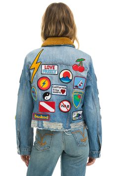 a woman wearing a jean jacket with patches on it