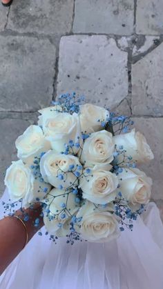 a bride's bouquet with white roses and baby's breath is held in her hand