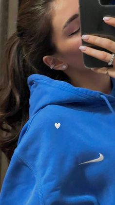 a woman taking a selfie with her cell phone while wearing a blue hoodie