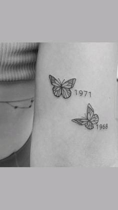 two butterflies on the side of a woman's leg with numbers and date tattooed