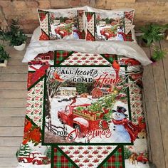 a bed with christmas themed comforters and pillows on top of wooden floor next to potted plants