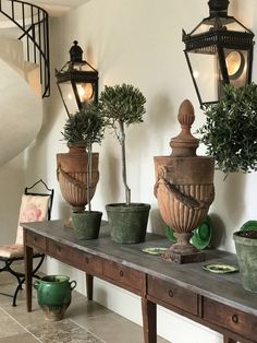 some potted plants are sitting on a table in front of a staircase and lanterns