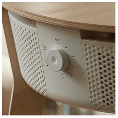 an electronic device is sitting on top of a wooden table with holes and rivets