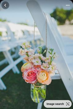 a vase filled with flowers sitting on top of a white chair next to an aisle